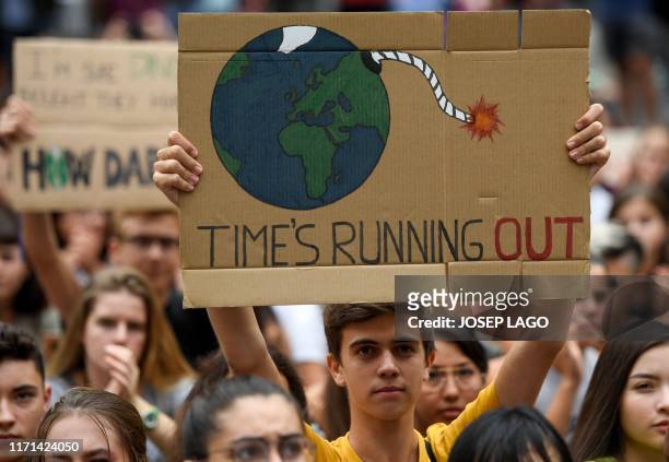 Demonstrator holds a placard reading "time is running out" during a global youth climate action strike in Barcelona, on September 27, 2019 at the end...