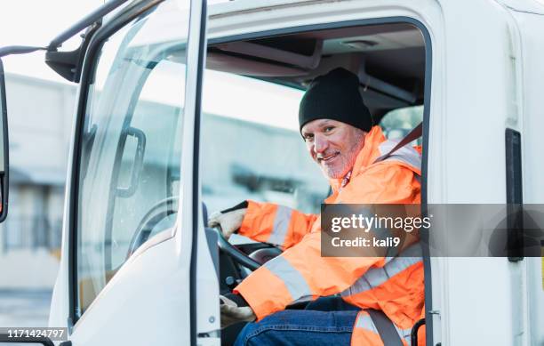 hispanic truck driver sitting in vehicle, at warehouse - truck driver stock pictures, royalty-free photos & images