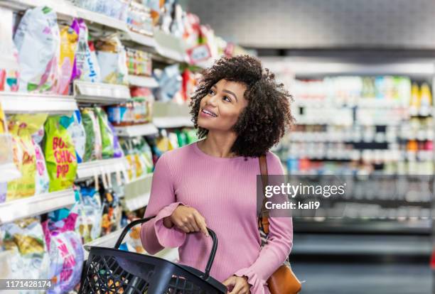 joven afroamericana comprando en supermercado - mirar alrededor fotografías e imágenes de stock