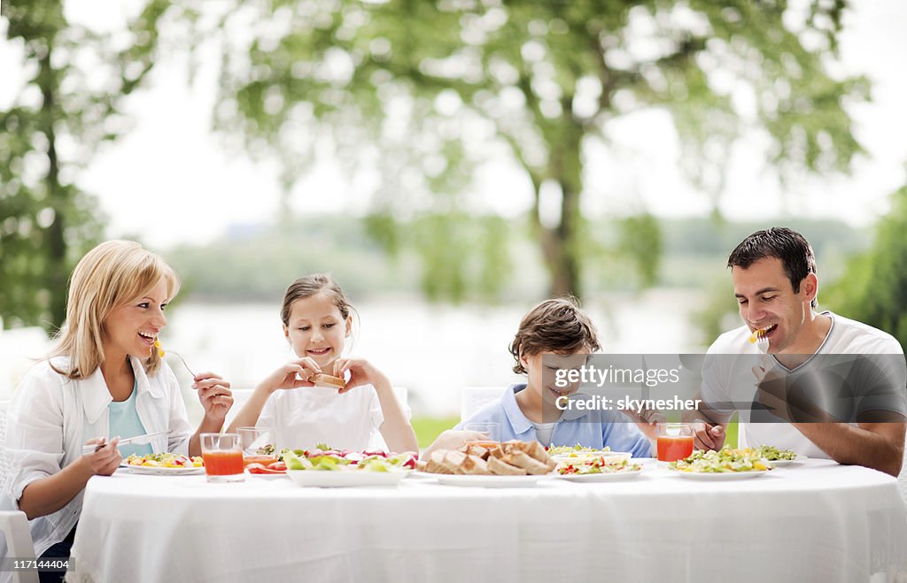 Happy family eating together outdoor.
