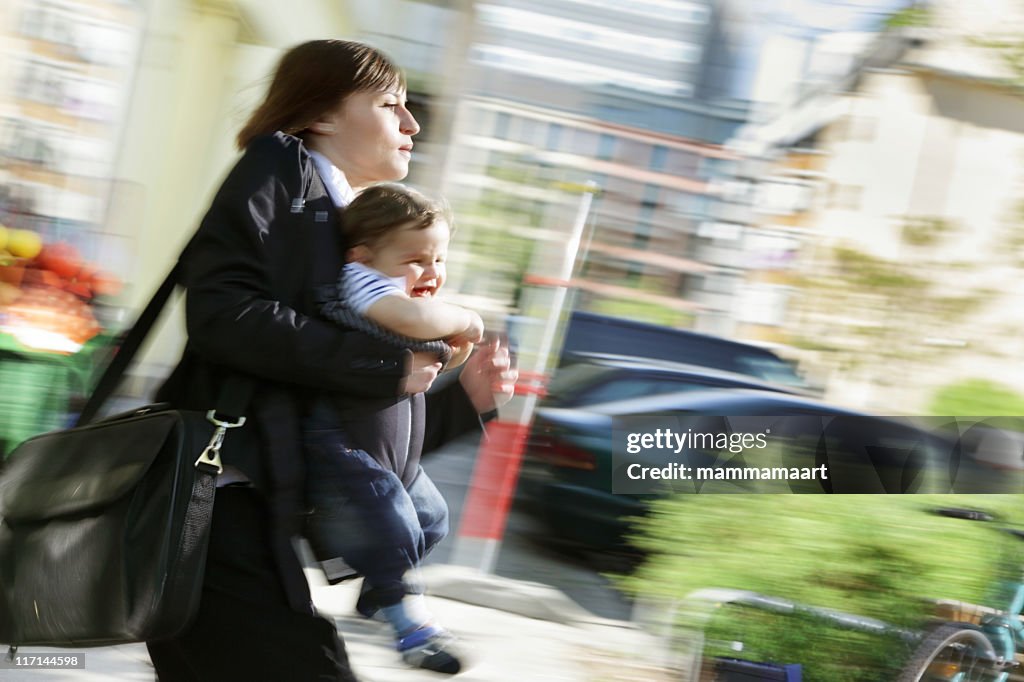 Working in a rush, mom carrying infant son outdoors