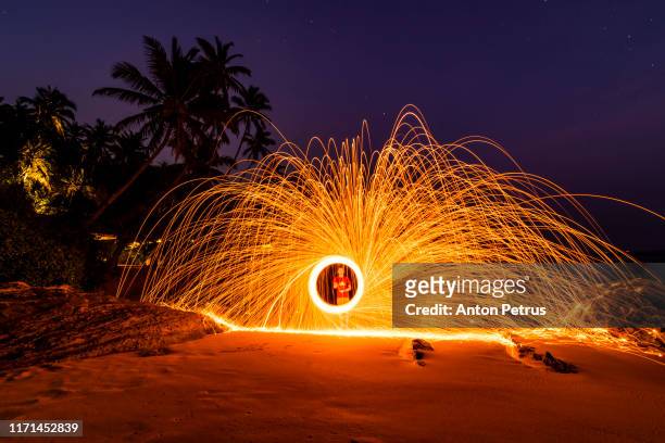 ring of fire spinning steel wool on the beach, - long exposure dancer stock-fotos und bilder