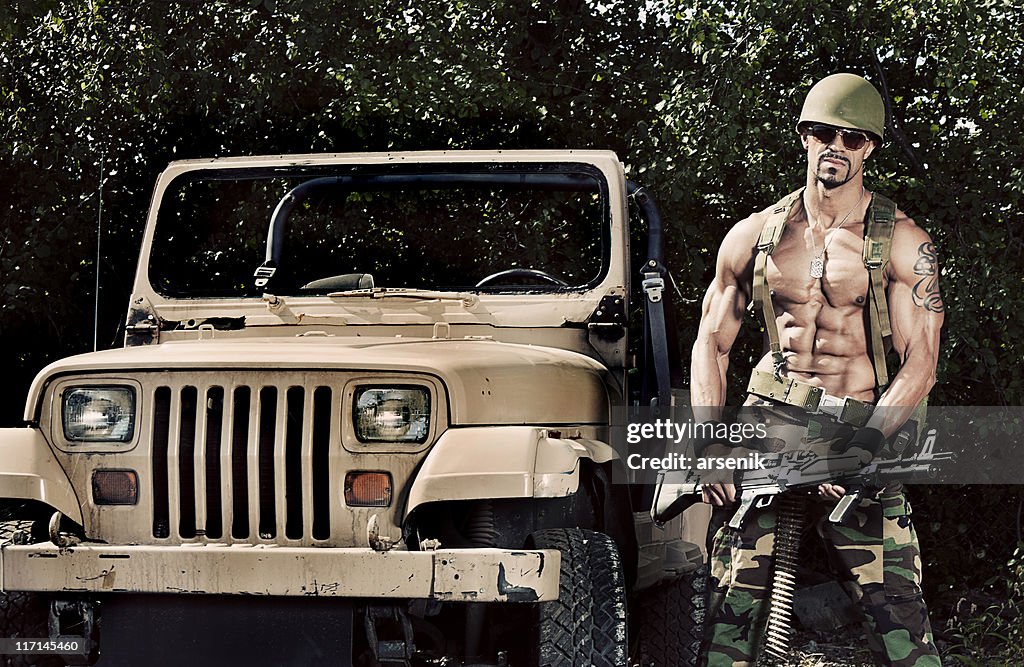 Soldier holding machine gun beside jeep