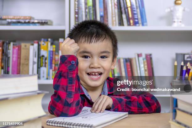 back to school. happy smiling pupil drawing at the desk. child in the class room with blackboard on background. alarm clock, pencils, books. - desk of student alarm clock books and pencils foto e immagini stock