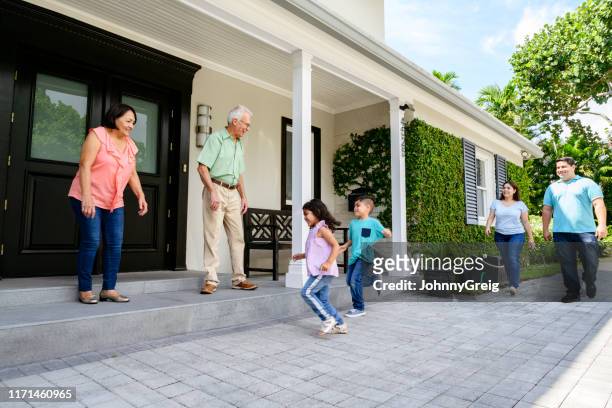 grandparents greeting family arriving at their home to a warm welcome - family smiling at front door stock pictures, royalty-free photos & images