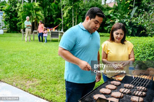volwassen hispanic paar barbecueën met familie in het weekend - backyard grilling stockfoto's en -beelden