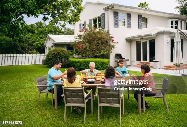 familia hispana disfrutando del almuerzo de barbacoa de verano en el patio trasero - casa de dos pisos fotografías e imágenes de stock