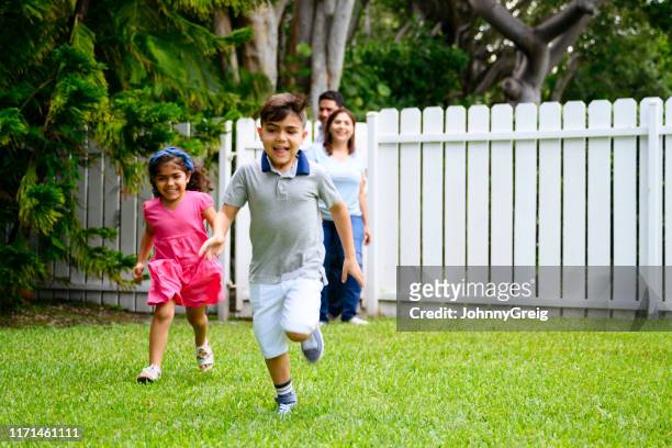energetic hispanic children returning home with parents - garden fence stock pictures, royalty-free photos & images