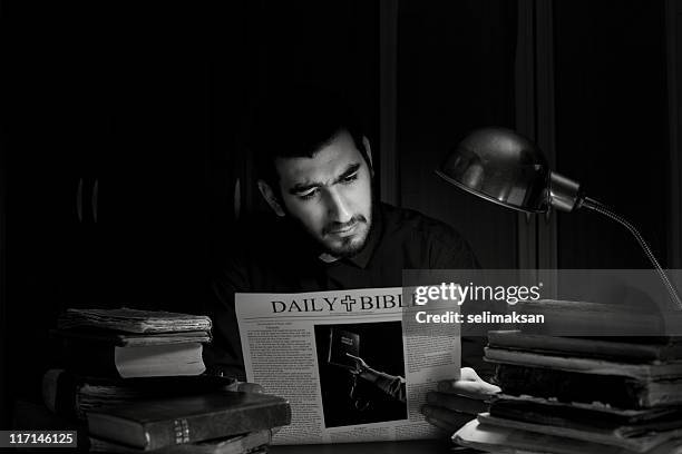 priest reading daily bible newspaper in dark. - paparazzi x posed stock pictures, royalty-free photos & images