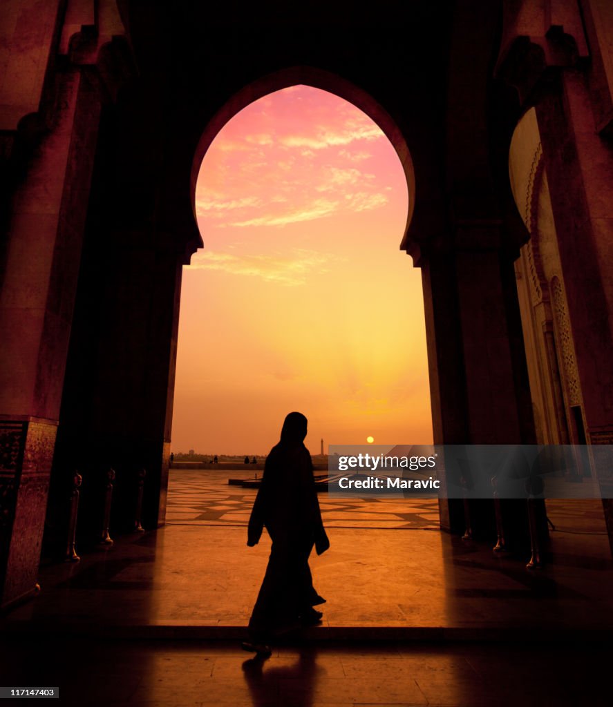 A man walking in a mosque during a sunset