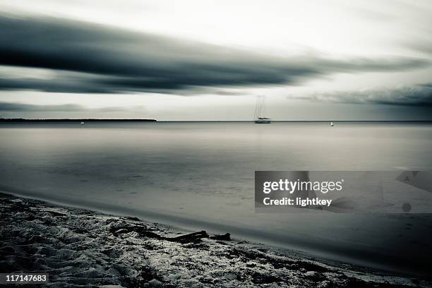 wolken über den strand - entsättigt stock-fotos und bilder