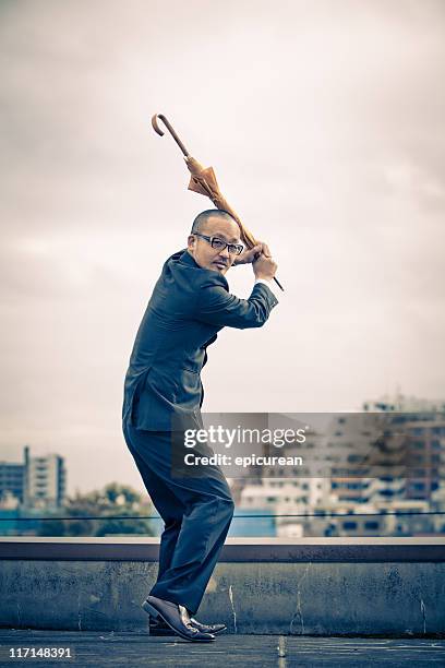 japanese businessman playing baseball with an umbrella - japanese baseball players strike stock pictures, royalty-free photos & images