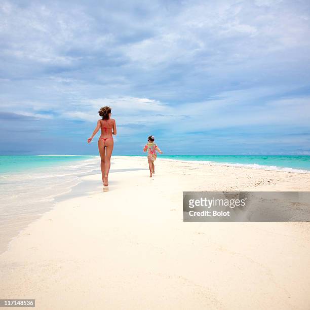mother in bikini running with daughter on tropical beach - string stockfoto's en -beelden