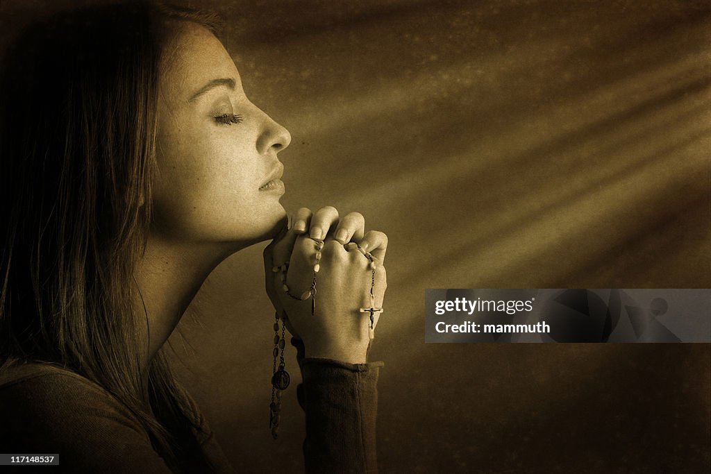 Praying young woman in divine light