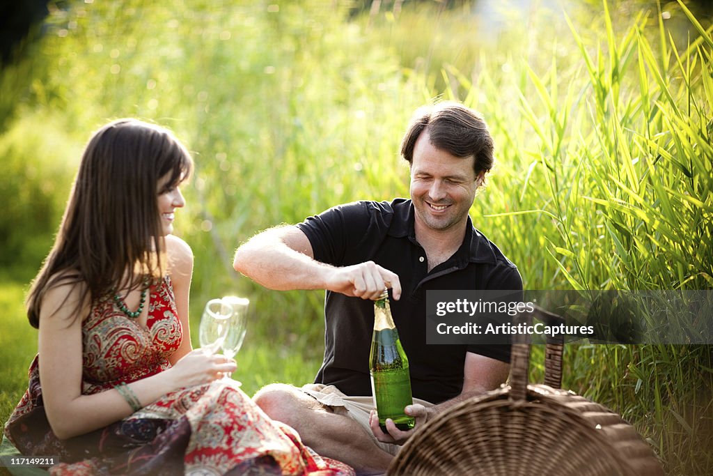 Couple Enjoying Romantic Picnic Outside with Wine Glasses