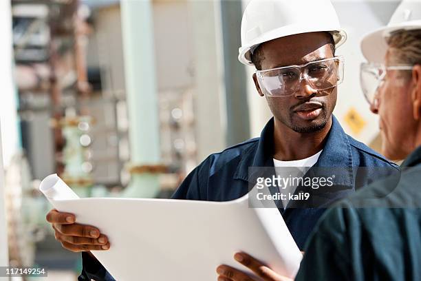 industrial workers reviewing plans - black helmet stock pictures, royalty-free photos & images