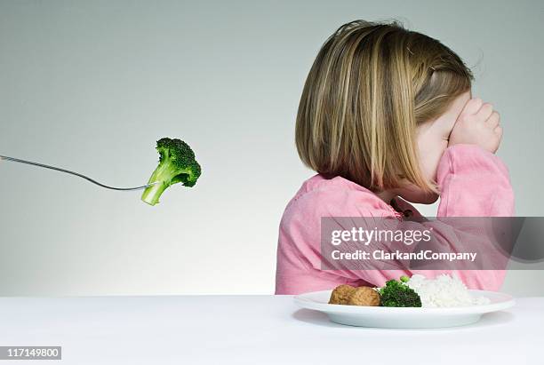 trying to get a child to eat her greens - weigeren stockfoto's en -beelden