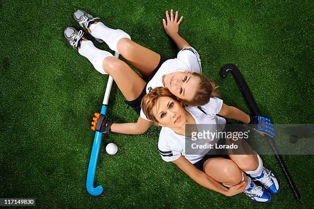 two female hockey players sitting at sport field - hockey player stockfoto's en -beelden