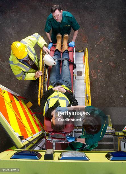 paramedics load patient into ambulance - building site accidents stock pictures, royalty-free photos & images