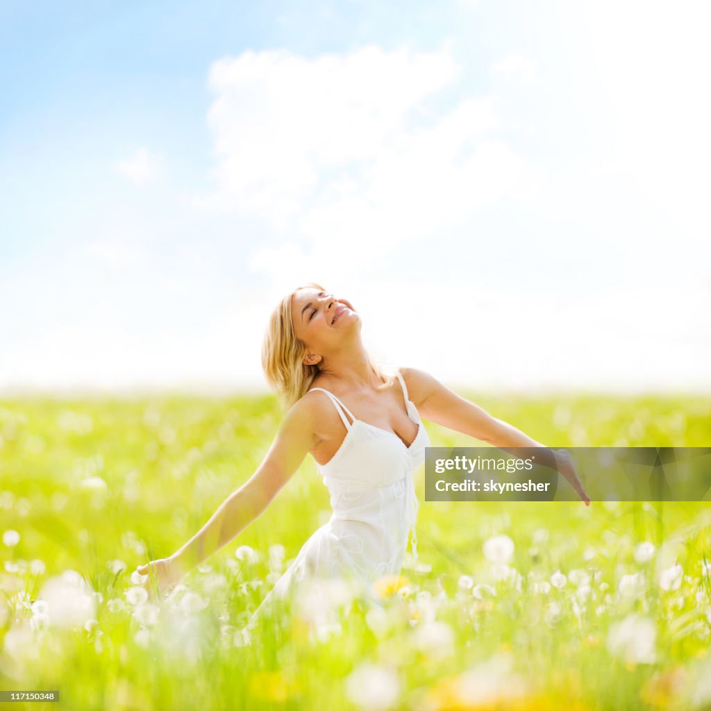Beautiful adult blonde standing on sunny field enjoying herself.