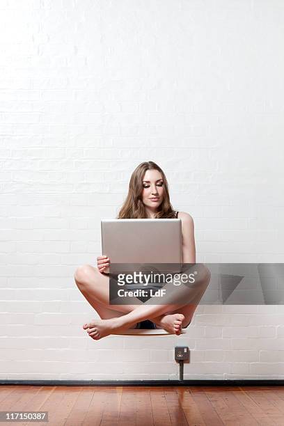 mujer joven usando una computadora portátil en la media de aire flotante - levitación fotografías e imágenes de stock