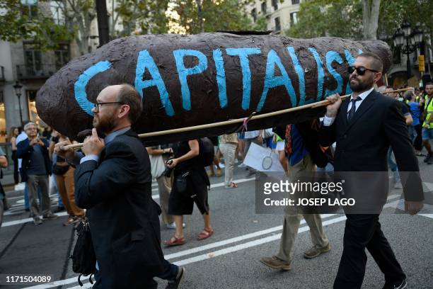 Demonstrators carry a sculpture depicting a turd with the legend "Capitalism" on it during a global youth climate action strike in Barcelona, on...