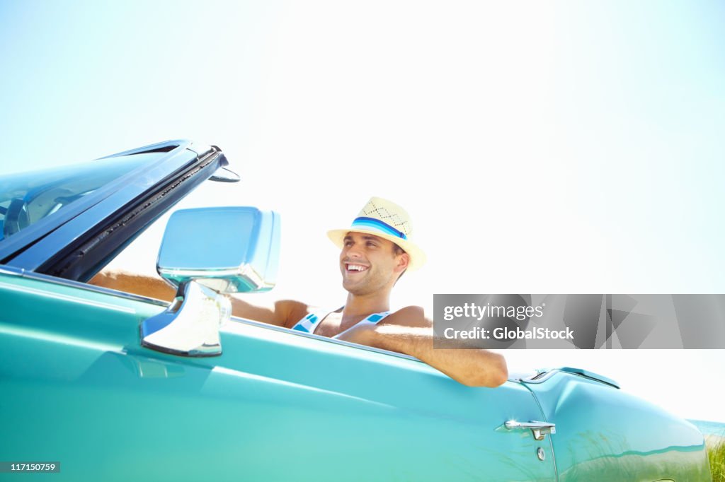 Smiling young man wearing hat while driving convertible car