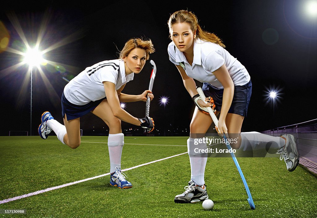 Two women playing field hockey