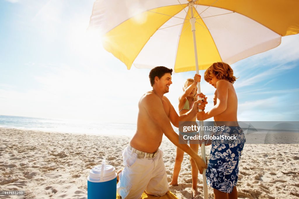 Familie mit Sonnenschirm am Strand an einem sonnigen Tag
