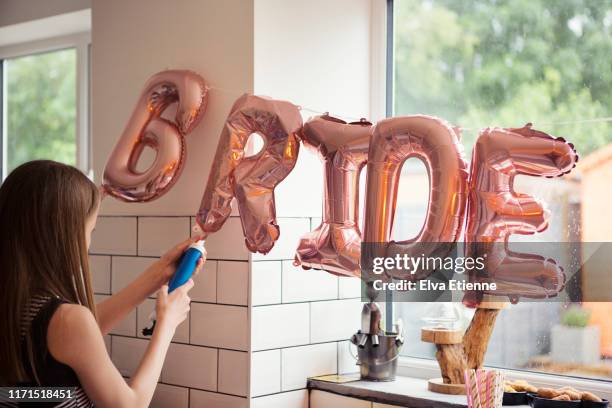 girl inflating metallic balloon decorations that spell out the word 'bride' for a hen party - junggesellinnenabschied stock-fotos und bilder