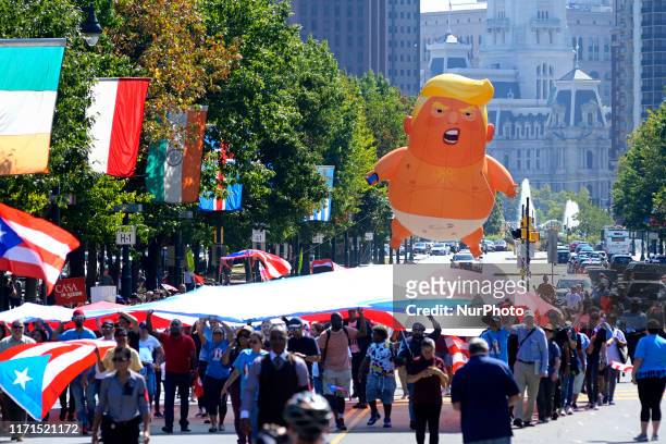 The Baby Trump balloon trails a large flag during the Peoples March for Puerto Rico, commemorating the second anniversary of Hurricane Marina, at a...
