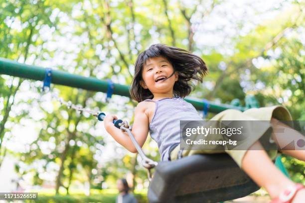 kind spielt auf schaukel - spielplatz einrichtung stock-fotos und bilder