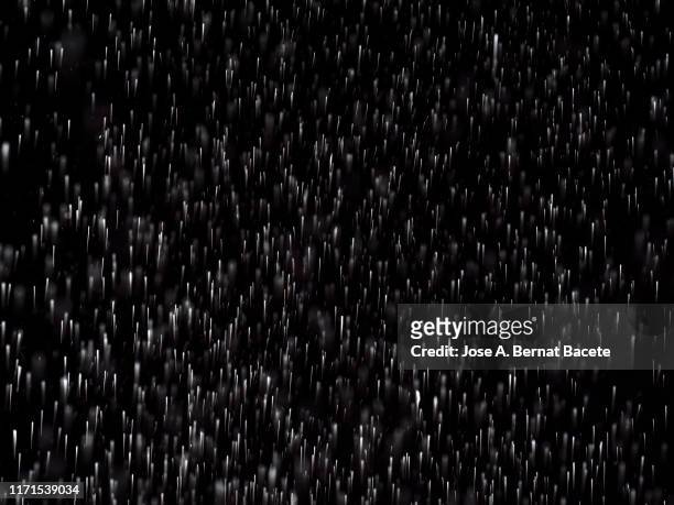 full frame of the textures formed  by the water jets to pressure with drops floating in the air of color white on a black background - torrential rain stockfoto's en -beelden