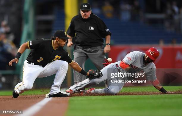 Jose Peraza of the Cincinnati Reds safely steals third base in front of Erik Gonzalez of the Pittsburgh Pirates and scores on an error during the...