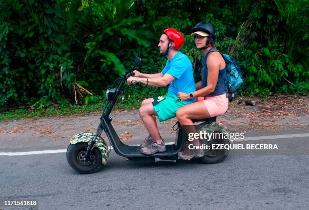 People drive an electric scooter in Puerto Viejo in Limon, Costa Rica, on September 27, 2019. - Costa Rica received the 2019 United Nations Champions...