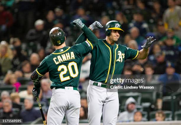 Matt Olson of the Oakland Athletics greets Mark Canha after hitting a two-run home run to take the lead over the Seattle Mariners in the seventh...