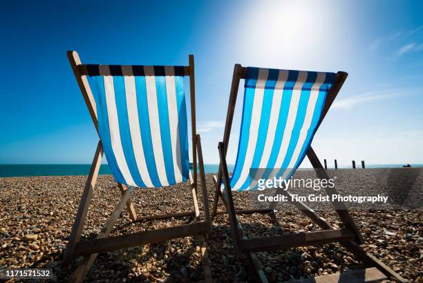 blue and white striped deck chairs and sun glare on the beach, brighton, uk - 熱波 ストックフォトと画像
