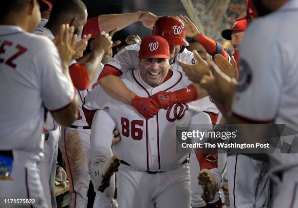 Washington Nationals second baseman Brian Dozier ride on the back of Ali Modami, one of the teams batting practice pitchers through the dugout to...