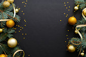 Black Christmas background with golden decorations, baubles, fir tree branches, confetti. Christmas holiday celebration, winter, New Year concept. Christmas banner mockup, greeting card template.