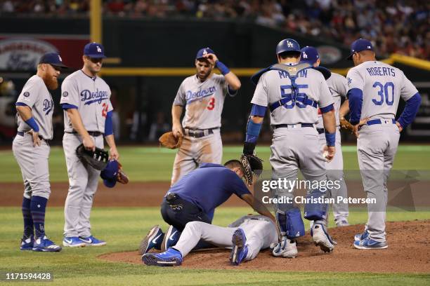 Relief pitcher Dustin May of the Los Angeles Dodgers is attended to by a team trainer after being hit by a line drive during the fourth inning of the...