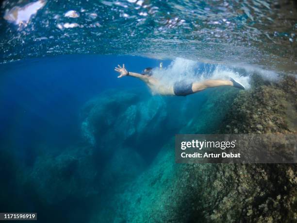 guy diving underwater in the paradise waters of costa brava shoreline in spain. - angel island stock pictures, royalty-free photos & images