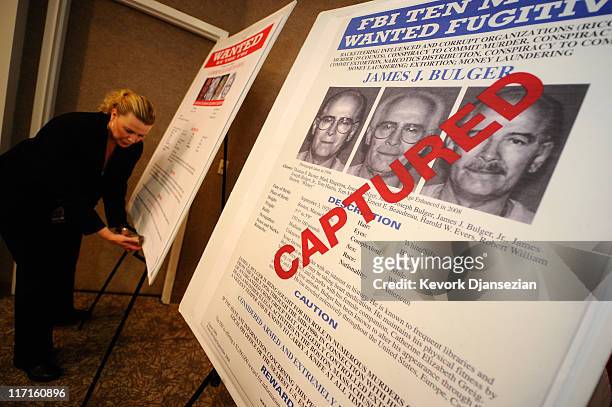 Mary Prang, Special Agent wit the FBI, adjusts a poster featuring fugitives Boston crime boss James "Whitey" Bulger along with his companion...