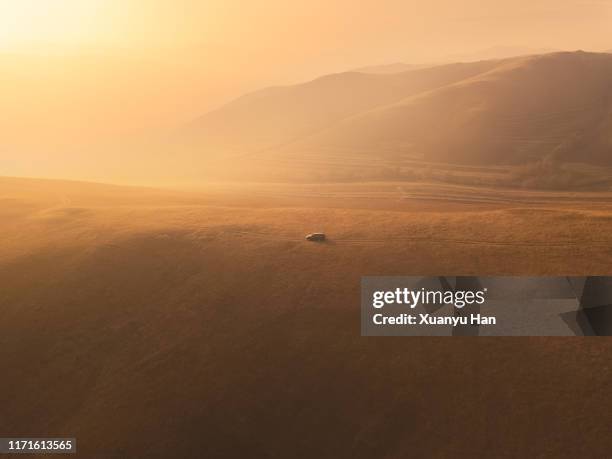 aerial view car driving in the mountains - dirt road landscape sunset stock-fotos und bilder
