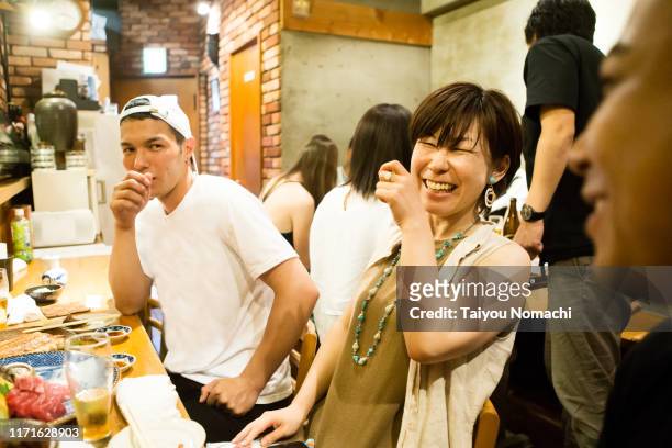 people of various ethnicities interacting at a japanese pub - 飲み会　日本 ストックフォトと画像