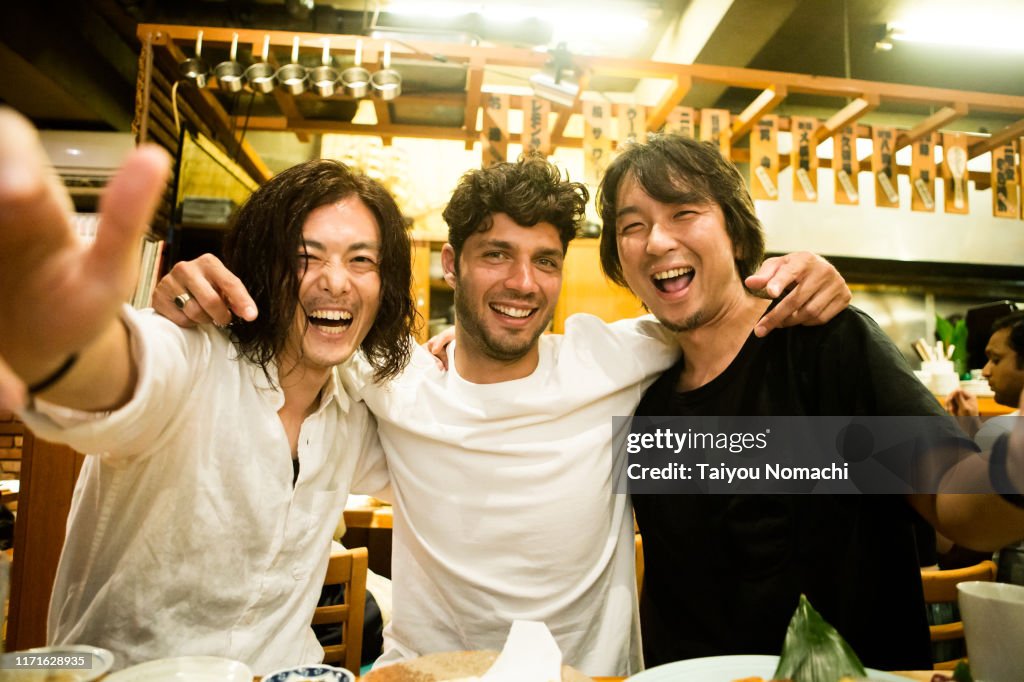 People of various ethnicities interacting at a Japanese izakaya