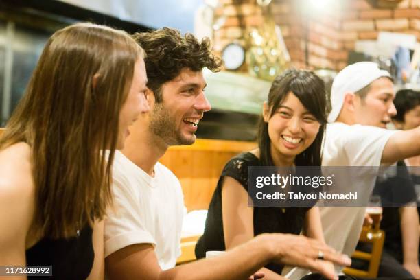 people of various ethnicities interacting at a japanese pub - 酒場　日本 ストックフォトと画像