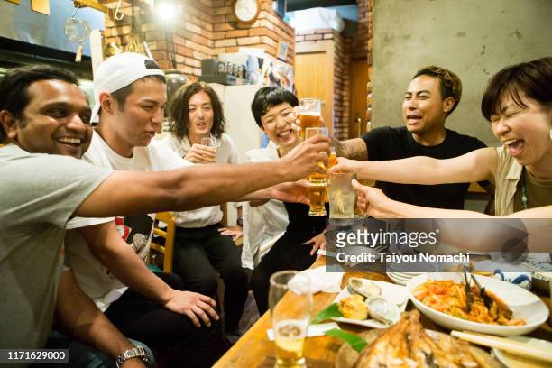 people of various ethnicities interacting at a japanese pub - 飲み会　日本 ストックフォトと画像