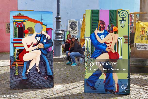 Vendors wait for tourists looking to be photographed with tango dancer cutouts in the famous Caminito street museum in La Boca neighborhood on March...