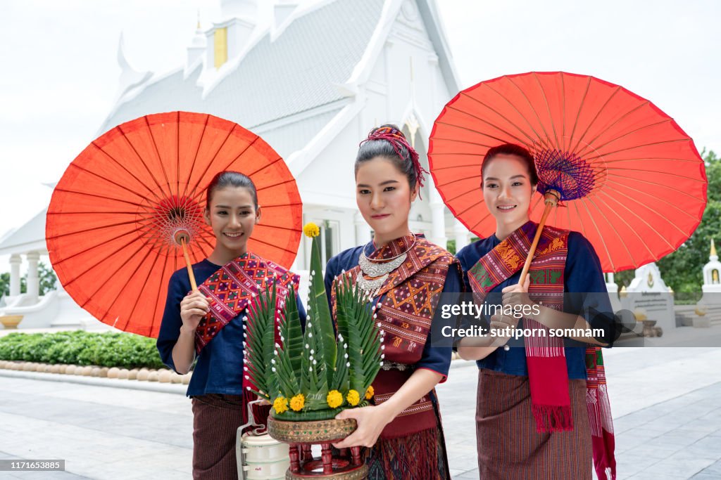 Three Thai girls dressed in traditional Isan traditional dress to go to the temple.