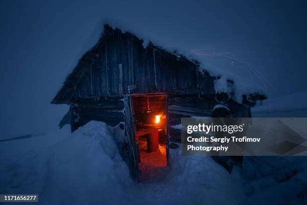 mountain hut with burning wood stove at winter night - fireplace forest stock pictures, royalty-free photos & images